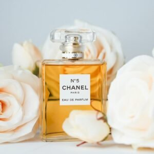 Chanel No 5 perfume bottle surrounded by elegant white roses, symbolizing luxury and femininity.